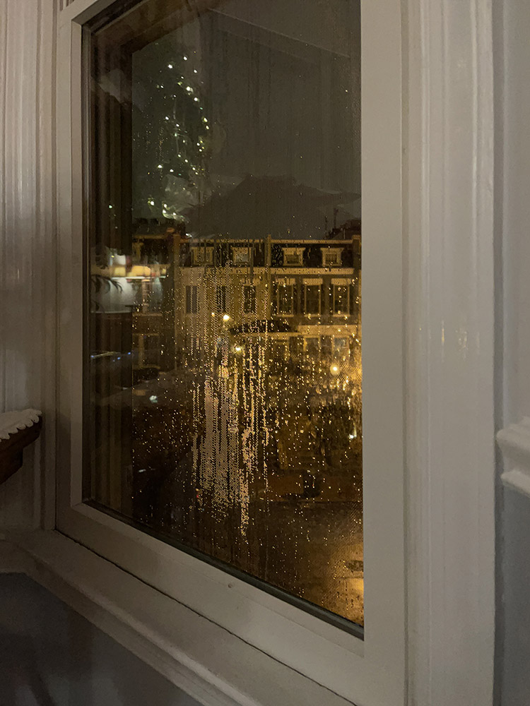 Photo of Window with Warm Toned Backlit Rain Droplets.